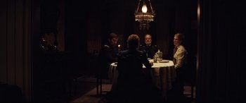 Movie still from “Hostiles” (2017), directed by Scott Cooper – A group of people sitting at a table with a candle; Wide shot, Over the shoulder angle