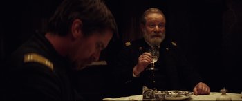 Movie still from “Hostiles” (2017), directed by Scott Cooper – Two men sitting at a table with a glass of wine; Close Up shot, Over the shoulder angle