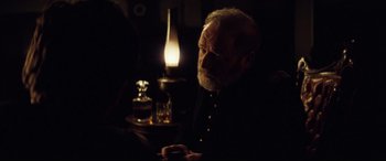 Movie still from “Hostiles” (2017), directed by Scott Cooper – An older man sitting in front of a lit candle; Close Up shot, Over the shoulder angle