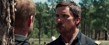 Movie still from “Hostiles” (2017), directed by Scott Cooper – A man with a beard and mustache is looking at another man with a beard; Close Up shot, Over the shoulder angle