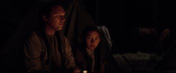Movie still from “Hostiles” (2017), directed by Scott Cooper – A man and a young girl are standing in front of a tent; Medium shot, Over the shoulder angle