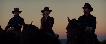 Movie still from “Hostiles” (2017), directed by Scott Cooper – A woman sitting on top of a horse at sunset; Medium shot, Low angle