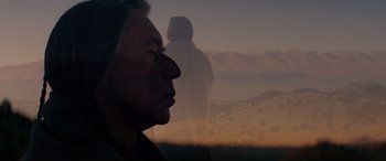 Movie still from “Hostiles” (2017), directed by Scott Cooper – A man with long black hair is looking out a window at the sky; Close Up shot, Low angle
