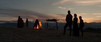 Movie still from “Hostiles” (2017), directed by Scott Cooper – A man standing in front of a fire on a hill; Wide shot, Low angle
