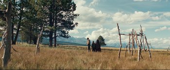 Movie still from “Hostiles” (2017), directed by Scott Cooper – A group of people standing in a grassy field; Extreme Wide shot, Low angle