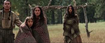 Movie still from “Hostiles” (2017), directed by Scott Cooper – A group of people standing next to each other in the grass; Wide shot, Low angle