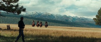 Movie still from “Hostiles” (2017), directed by Scott Cooper – A group of people riding horses through a field; Extreme Wide shot, Low angle