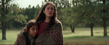 Movie still from “Hostiles” (2017), directed by Scott Cooper – A woman wrapped in a blanket with a young girl; Medium shot, Low angle