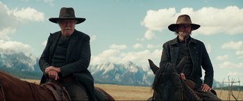 Movie still from “Hostiles” (2017), directed by Scott Cooper – Two men on horses in a field with mountains in the background; Medium shot, Low angle