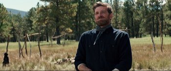 Movie still from “Hostiles” (2017), directed by Scott Cooper – A man in a black shirt is standing in a field; Medium shot, Over the shoulder angle