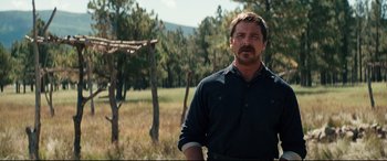 Movie still from “Hostiles” (2017), directed by Scott Cooper – A person standing in a field with trees in the background; Medium shot, Low angle