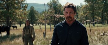 Movie still from “Hostiles” (2017), directed by Scott Cooper – A man standing next to a tree in a field; Medium shot, Over the shoulder angle