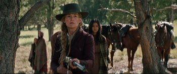 Movie still from “Hostiles” (2017), directed by Scott Cooper – A woman holding a gun while standing next to a horse; Medium shot, Low angle