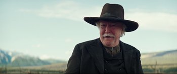 Movie still from “Hostiles” (2017), directed by Scott Cooper – An older man with a mustache wearing a hat; Close Up shot, Over the shoulder angle