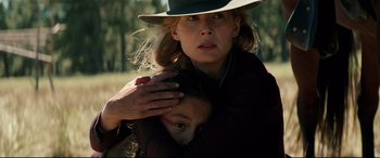Movie still from “Hostiles” (2017), directed by Scott Cooper – A woman holding a child in her arms and wearing a cowboy hat; Close Up shot, Over the shoulder angle