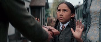 Movie still from “Hostiles” (2017), directed by Scott Cooper – A young girl in a school uniform is looking at a man; Close Up shot, Over the shoulder angle
