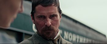 Movie still from “Hostiles” (2017), directed by Scott Cooper – A person wearing a suit and tie; Close Up shot, Low angle