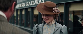 Movie still from “Hostiles” (2017), directed by Scott Cooper – A woman wearing a brown hat and a blue dress; Close Up shot, Over the shoulder angle