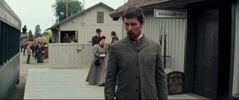 Movie still from “Hostiles” (2017), directed by Scott Cooper – A man with a beard standing in front of a group of people; Medium shot, Over the shoulder angle