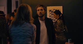 Movie still from “The Night Eats the World” (2018), directed by Dominique Rocher – A man and two women standing in front of a mirror; Medium shot, Over the shoulder angle