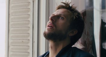 Movie still from “The Night Eats the World” (2018), directed by Dominique Rocher – A man with a beard looking up into the sky; Close Up shot, Low angle