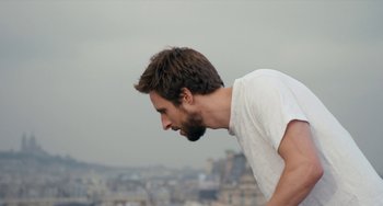 Movie still from “The Night Eats the World” (2018), directed by Dominique Rocher – A man with a beard is standing on a hill; Close Up shot, Low angle