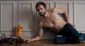 Movie still from “The Night Eats the World” (2018), directed by Dominique Rocher – A shirtless man sitting on the floor next to a box of pills; Medium shot, High angle