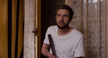 Movie still from “The Night Eats the World” (2018), directed by Dominique Rocher – A man holding a baseball bat in a room; Close Up shot, Over the shoulder angle