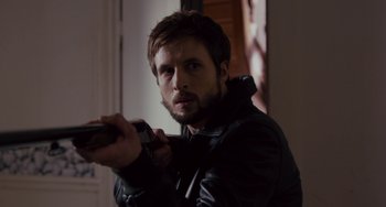 Movie still from “The Night Eats the World” (2018), directed by Dominique Rocher – A man in a leather jacket holding a cell phone; Close Up shot, Over the shoulder angle