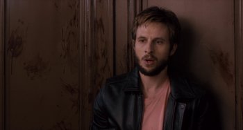 Movie still from “The Night Eats the World” (2018), directed by Dominique Rocher – A man in a leather jacket looking at the camera; Close Up shot, Over the shoulder angle