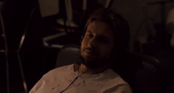 Movie still from “The Night Eats the World” (2018), directed by Dominique Rocher – A man with headphones sitting in a chair; Close Up shot, High angle