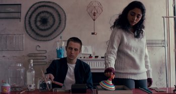 Movie still from “The Night Eats the World” (2018), directed by Dominique Rocher – A man and a woman sitting at a table; Medium shot, Low angle