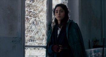 Movie still from “The Night Eats the World” (2018), directed by Dominique Rocher – A woman standing in front of a window; Medium shot, Low angle