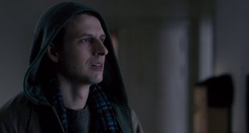 Movie still from “The Night Eats the World” (2018), directed by Dominique Rocher – A man wearing a hooded jacket and a scarf; Close Up shot, Over the shoulder angle