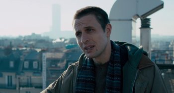 Movie still from “The Night Eats the World” (2018), directed by Dominique Rocher – A person wearing a jacket and a scarf; Close Up shot, Over the shoulder angle