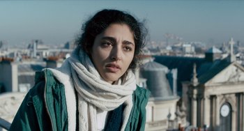 Movie still from “The Night Eats the World” (2018), directed by Dominique Rocher – A young woman wearing a white scarf and a green jacket; Close Up shot, Low angle