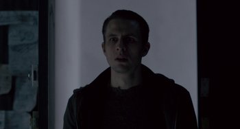 Movie still from “The Night Eats the World” (2018), directed by Dominique Rocher – A man standing in the dark with his mouth open; Close Up shot, Low angle