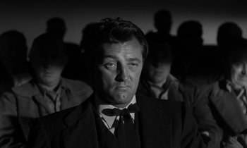 Movie still from “The Night of the Hunter” (1955), directed by Charles Laughton – A black and white photo of a man in a suit and bow tie; Close Up shot, Low angle