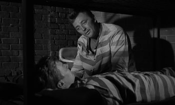 Movie still from “The Night of the Hunter” (1955), directed by Charles Laughton – A man sitting next to another man on a bed; Medium shot, Over the shoulder angle