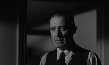 Movie still from “The Night of the Hunter” (1955), directed by Charles Laughton – An older man wearing a suit and a tie; Close Up shot, Low angle