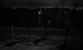 Movie still from “The Night of the Hunter” (1955), directed by Charles Laughton – A man standing next to a fence at night; Extreme Wide shot, Low angle