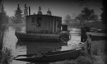Movie still from “The Night of the Hunter” (1955), directed by Charles Laughton – An old boat sits in the middle of the water; Extreme Wide shot, High angle
