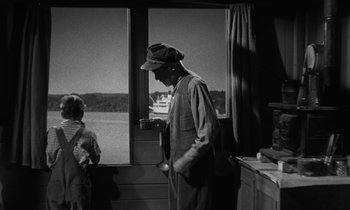 Movie still from “The Night of the Hunter” (1955), directed by Charles Laughton – An older man standing in front of a window; Medium shot, Over the shoulder angle