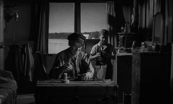 Movie still from “The Night of the Hunter” (1955), directed by Charles Laughton – Two men sitting at a table in front of a window; Medium shot, Low angle