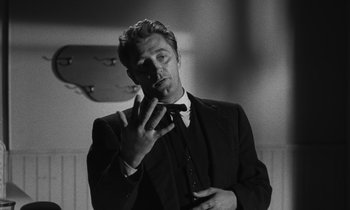 Movie still from “The Night of the Hunter” (1955), directed by Charles Laughton – A black and white photo of a man smoking a cigarette; Close Up shot, Low angle