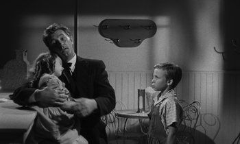 Movie still from “The Night of the Hunter” (1955), directed by Charles Laughton – An old photo of a man holding a baby and a little boy; Medium shot, Over the shoulder angle