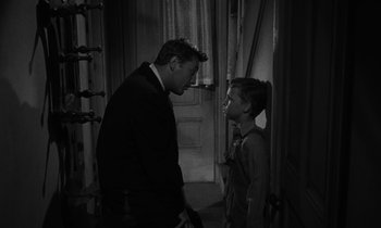 Movie still from “The Night of the Hunter” (1955), directed by Charles Laughton – A black and white photo of a man and a young boy; Medium shot, Over the shoulder angle