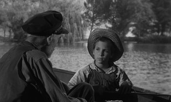 Movie still from “The Night of the Hunter” (1955), directed by Charles Laughton – An older man and a young boy sitting in a rowboat; Medium shot, Over the shoulder angle