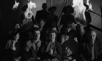 Movie still from “The Night of the Hunter” (1955), directed by Charles Laughton – A group of people sitting in front of a tent; Medium shot, High angle