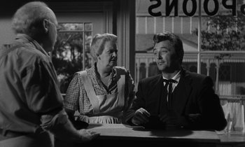 Movie still from “The Night of the Hunter” (1955), directed by Charles Laughton – A man and a woman sitting at a table in front of another man; Medium shot, Over the shoulder angle